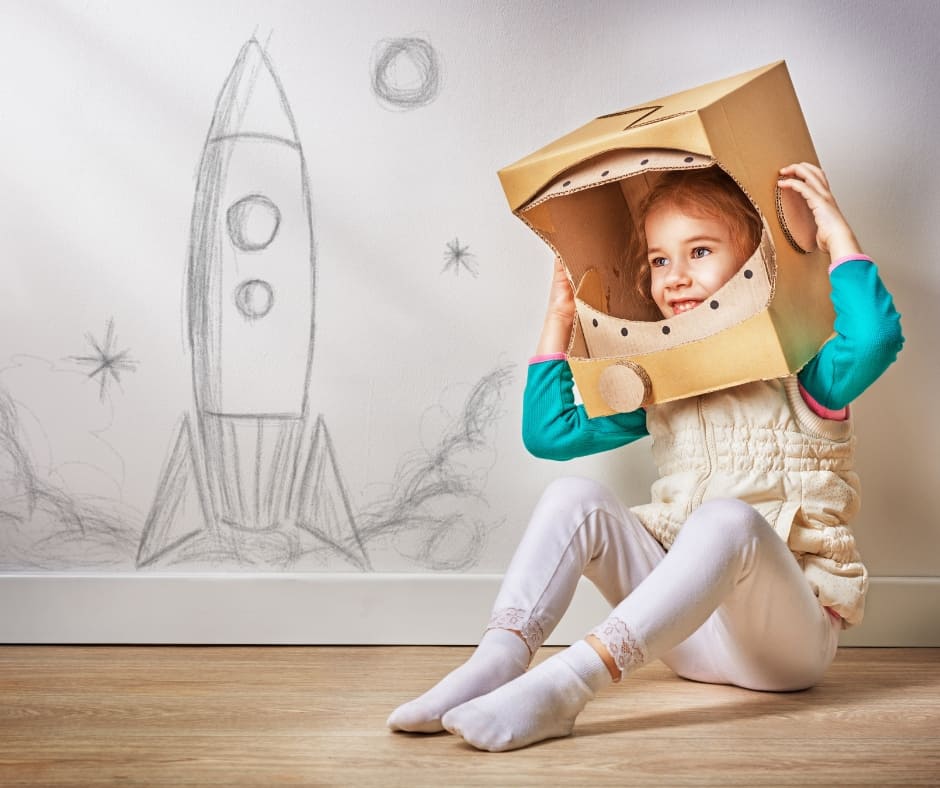 child playing make believe and using art to build a space ship out of cardboard
