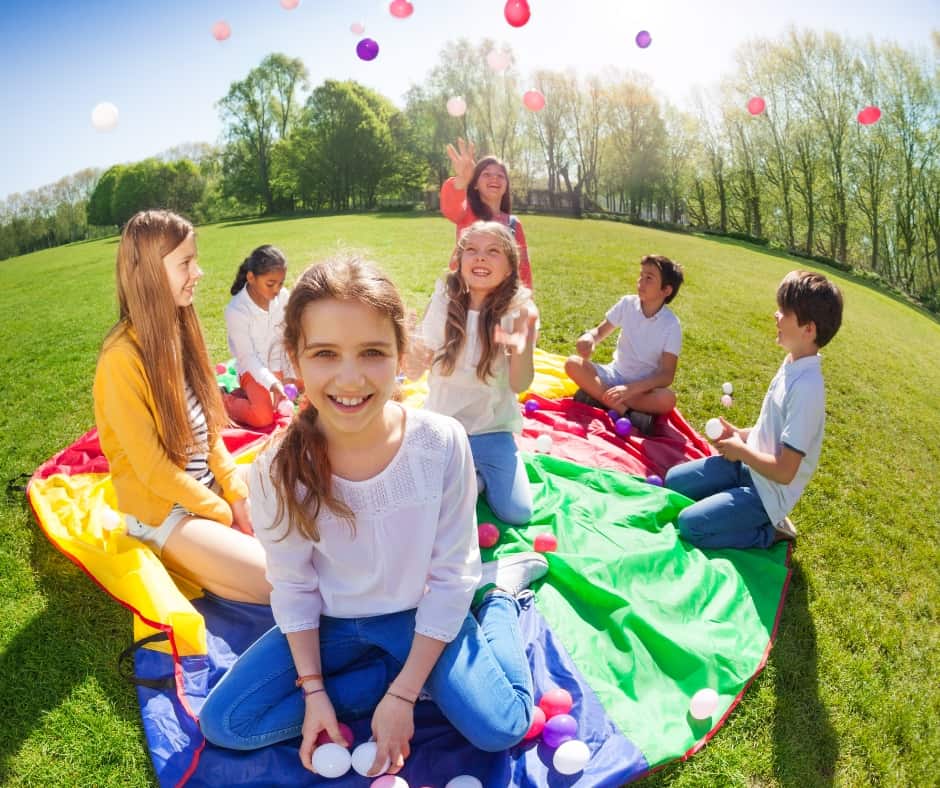 kids enjoying a kite and balloons in a field in the summer