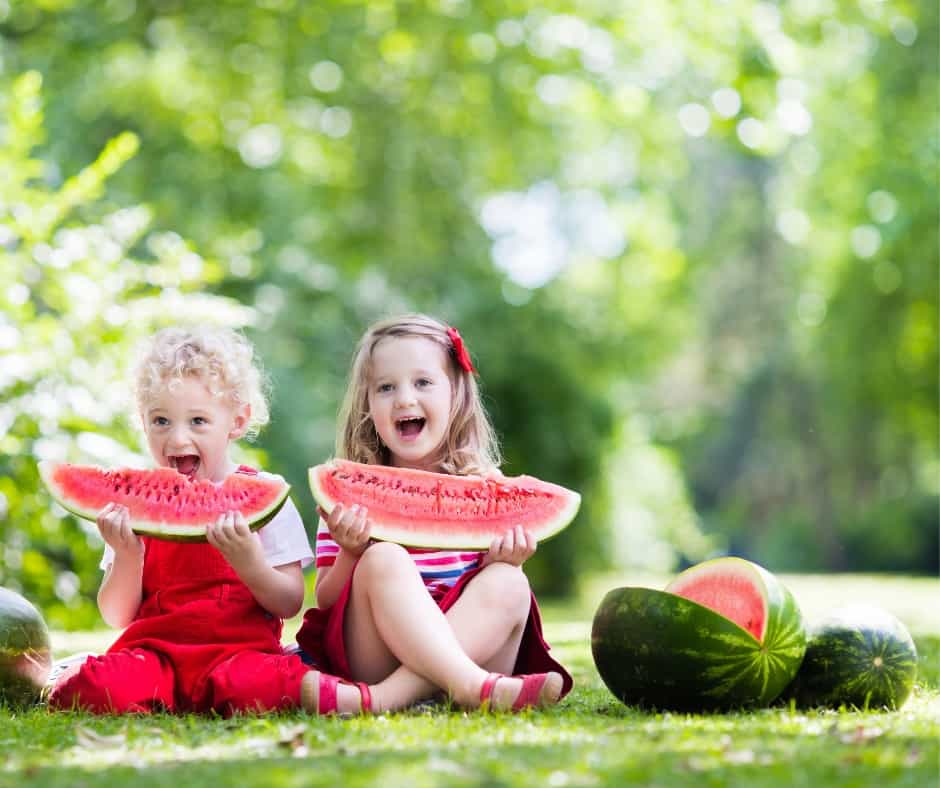 two girls enjoying watermelon on a summer picnic