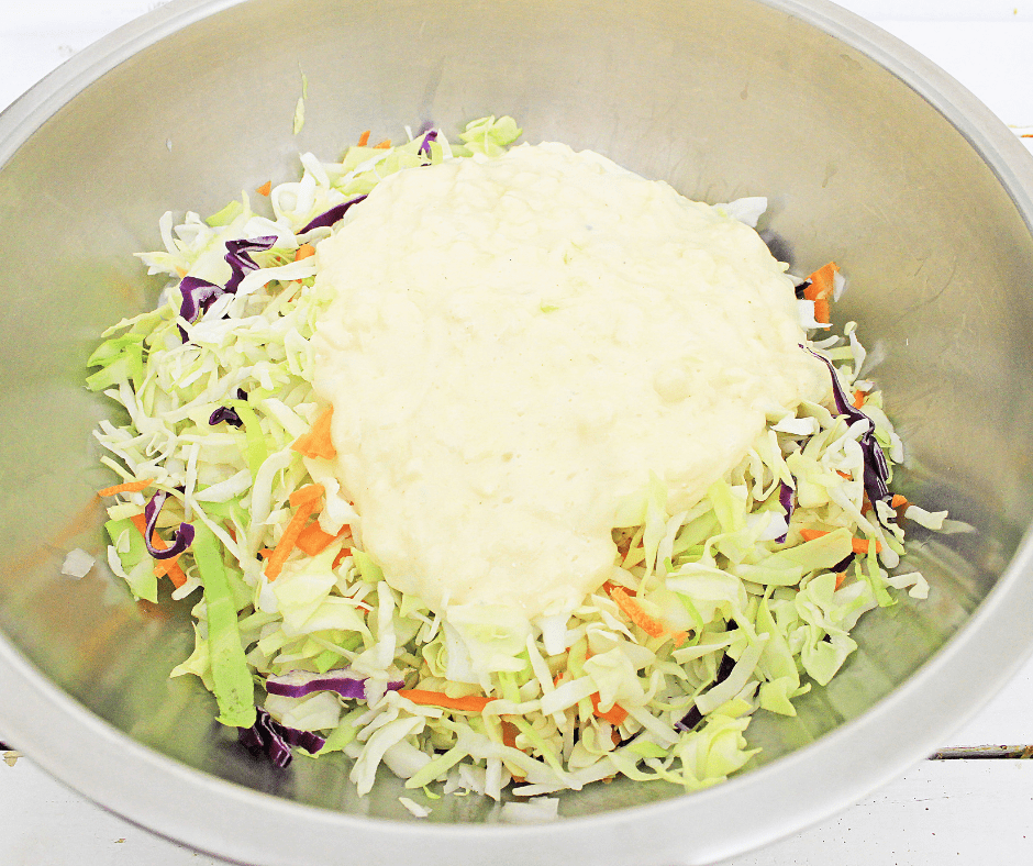 Mixing bowl with fresh coleslaw mix topped with pineapple coleslaw dressing