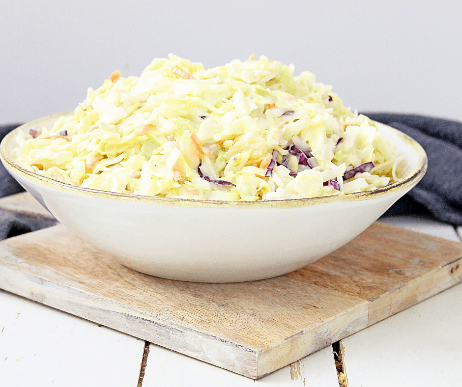Bowl of tangy pineapple coleslaw on wooden board