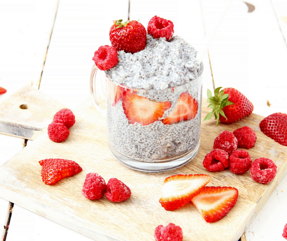 cup of coconut milk chia pudding with strawberries and raspberries on a cutting board
