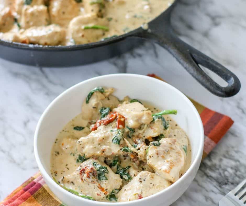 skillet and bowl holding creamy garlic sauce and sautéed chicken