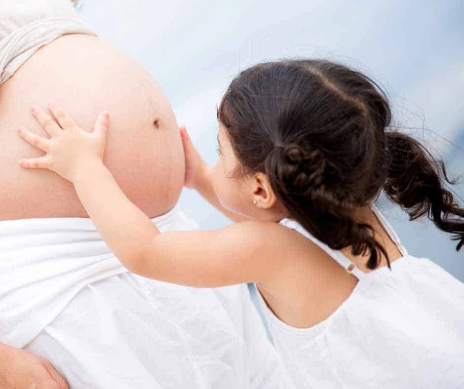 toddler girl holding mom's pregnant belly