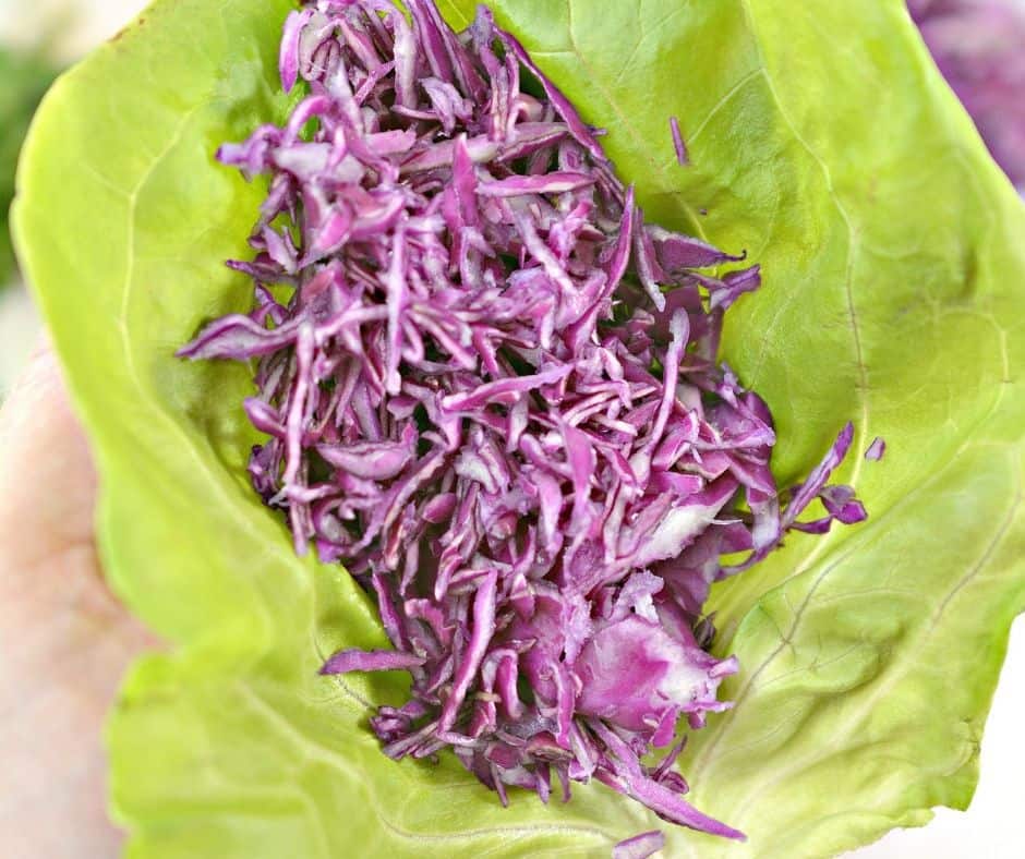 purple cabbage slaw in a Bibb lettuce leaf to prep for Caribbean baja shrimp tacos