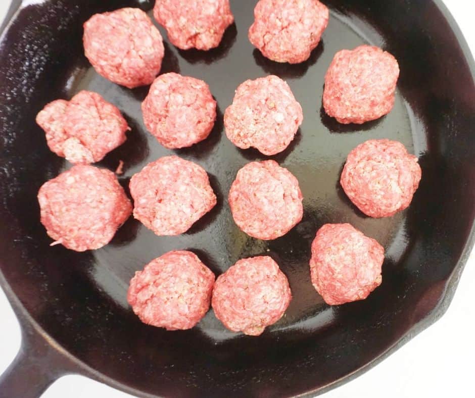 uncooked meatballs in a cast iron skillet