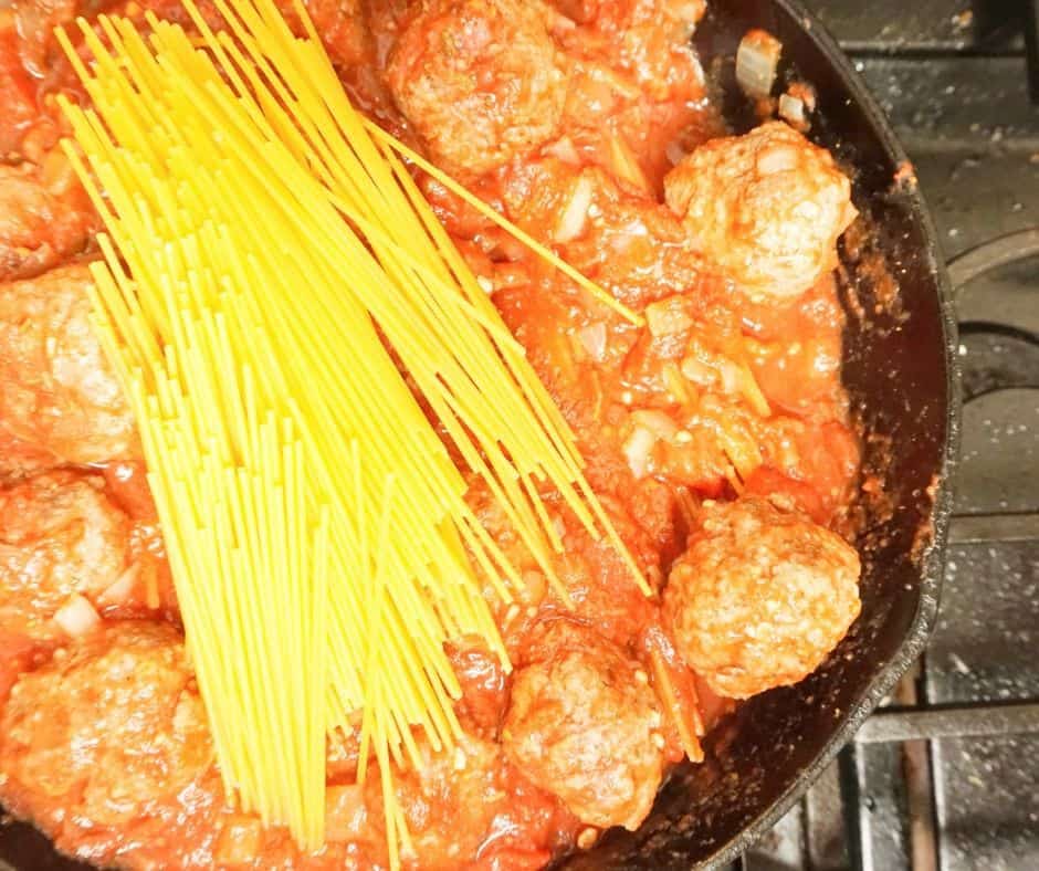 cooking spaghetti in a skillet with meatballs for an easy one dish weeknight family meal idea