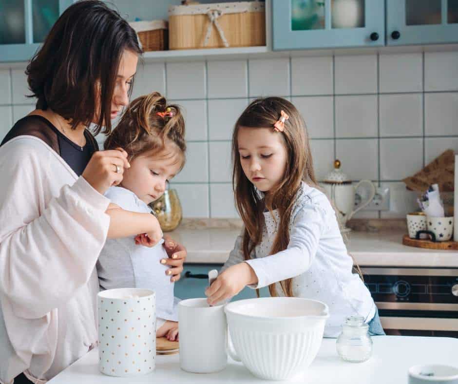 mom cooking with her two preschool aged daughters