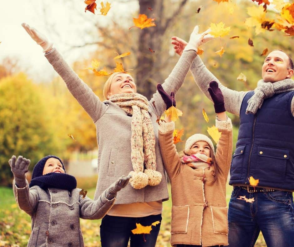 family playing in fall leaves together