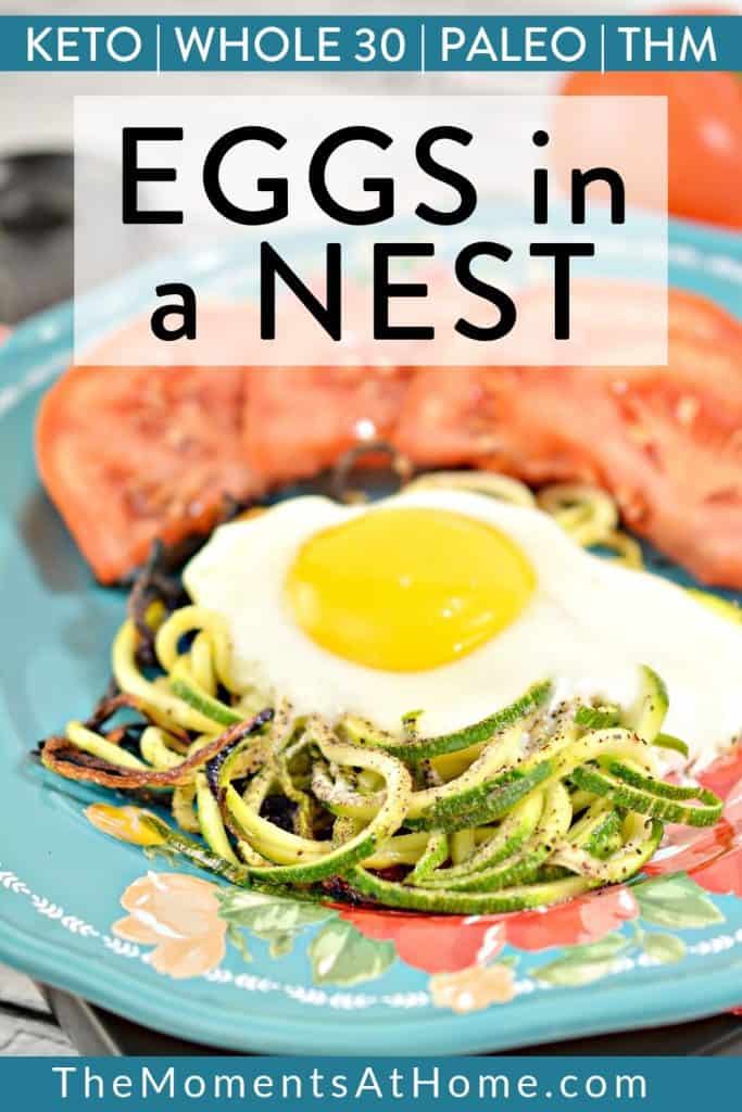 sunny side up egg on zoodles on a blue plate with tomato wedges with text "keto, paleo, whole 30, THM zucchini eggs in a nest" by the moments at home