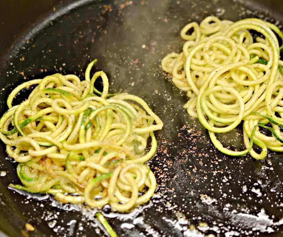 two zucchini piles in a skillet with garlic oil in preparation for Keto Eggs in a nest