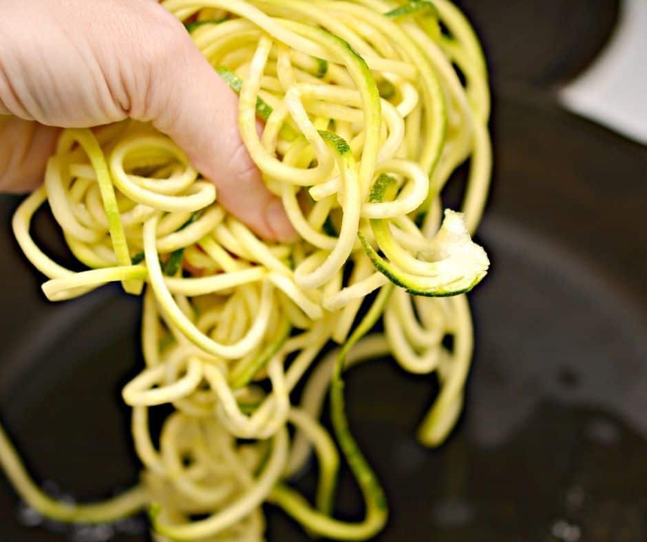 zoodles being added to a skillet