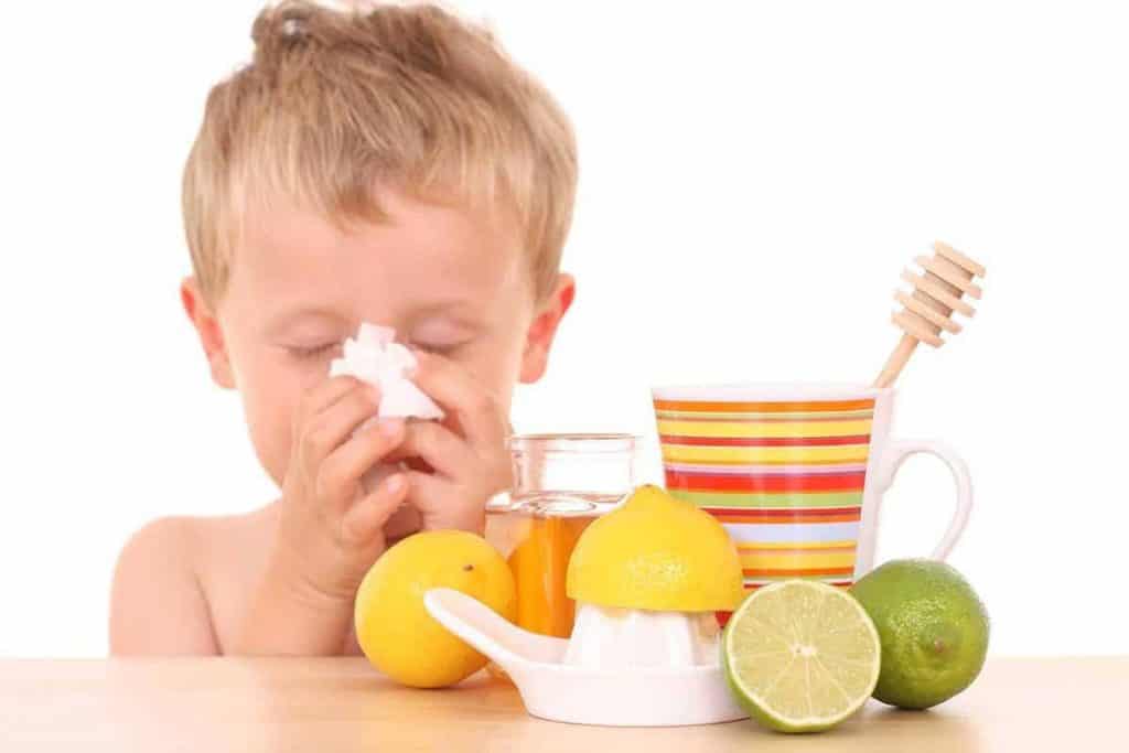 child wiping nose and has lemon and honey