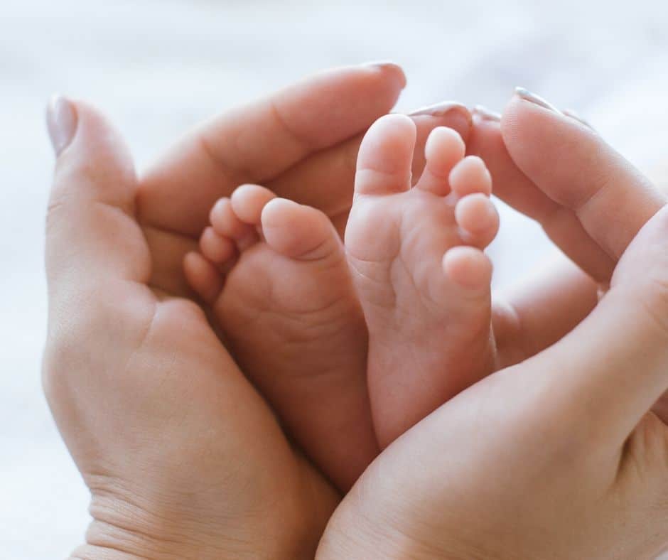 mom's hands cupping newborn feet