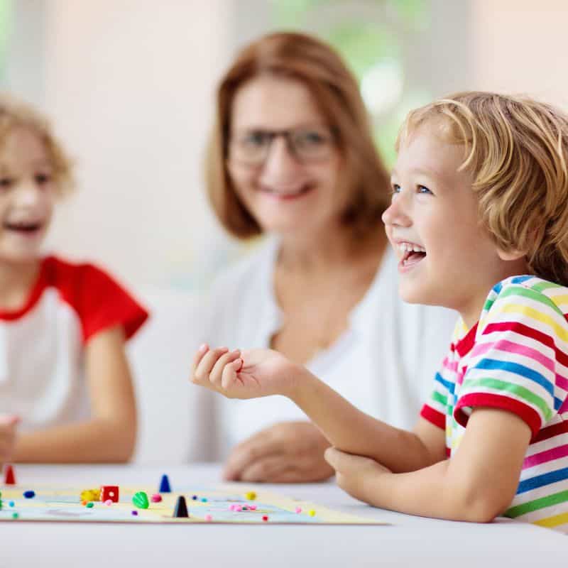 board game being played by a mom and two kids; family have fun playing board games