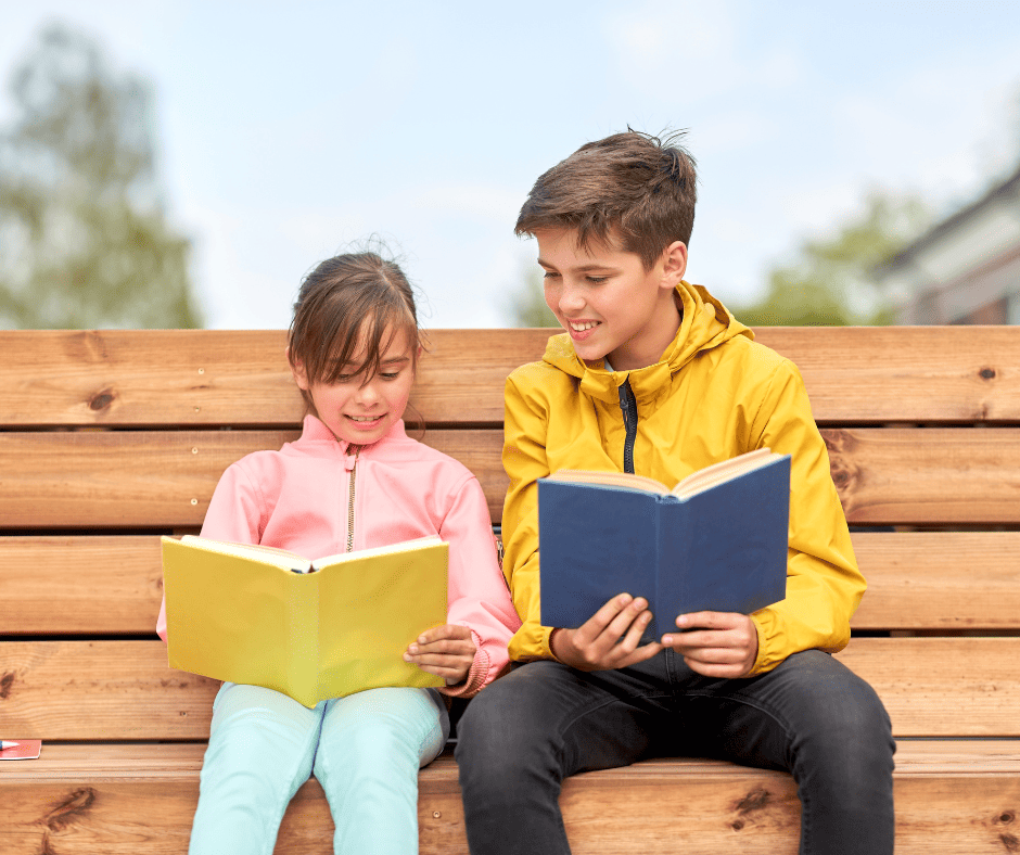 older boy sitting on a bench with a book next to a younger girl, also reading