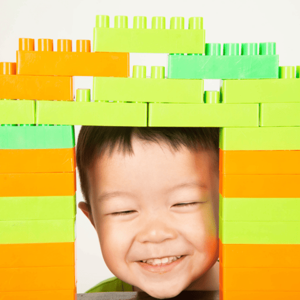 child playing with building bricks and smiling