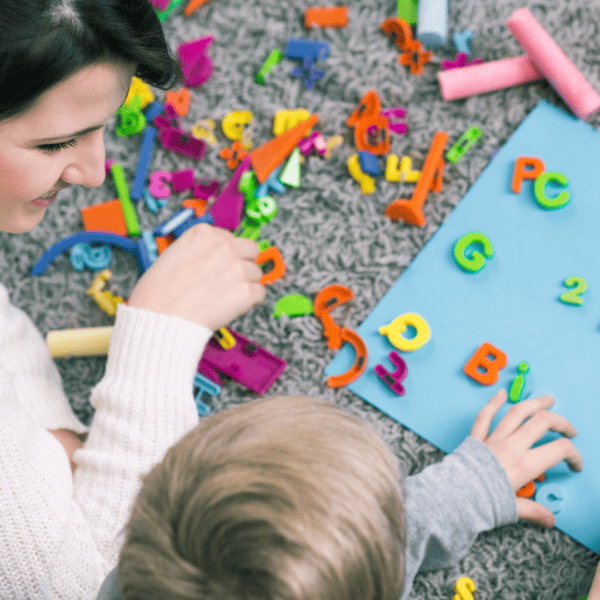 mom and child playing with plastic letters while sitting on the floor