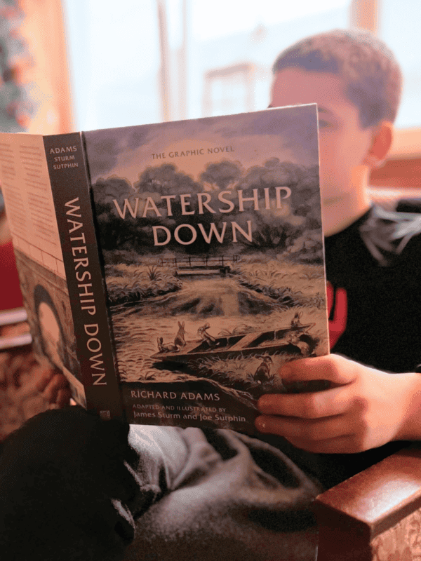 boy reading Watership Down at home